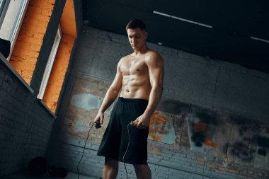 Jimnastik yaparken ip atlayan yakışıklı genç adam.