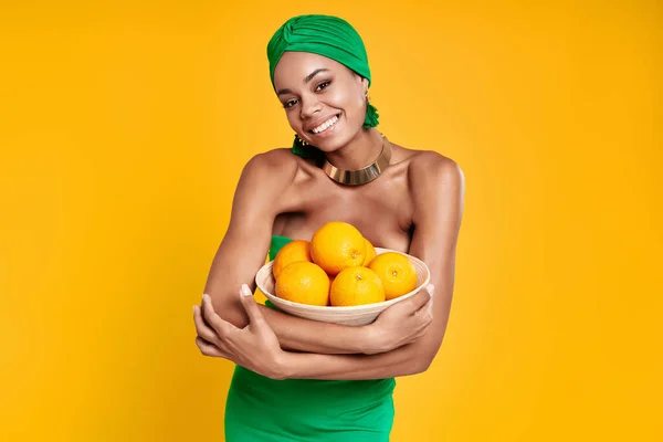 Atraktivní Africká Žena Tradičním Oblečení Drží Pomeranče Usmívá Žlutém Pozadí — Stock fotografie