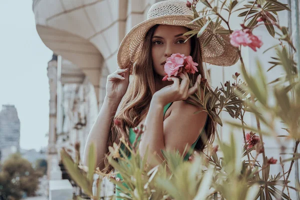 Όμορφη Νεαρή Γυναίκα Κομψό Καπέλο Μυρίζει Λουλούδια Ενώ Στέκεται Στο — Φωτογραφία Αρχείου