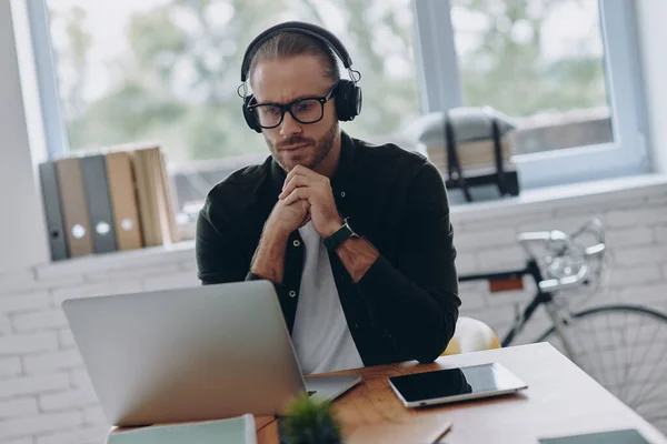 Hombre Concentrado Auriculares Mirando Portátil Mientras Está Sentado Lugar Trabajo — Foto de Stock