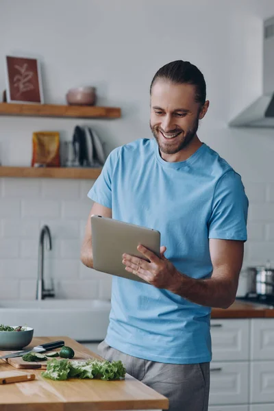 Giovane Allegro Utilizzando Tablet Digitale Mentre Prepara Cibo Cucina Domestica — Foto Stock