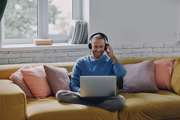 Hombre Guapo Auriculares Mirando Computadora Portátil Sonriendo Mientras Está Sentado — Foto de Stock