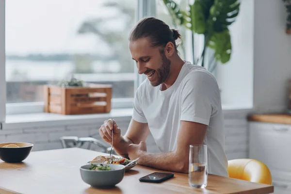 Joven Alegre Disfrutando Del Almuerzo Mientras Está Sentado Mostrador Cocina —  Fotos de Stock