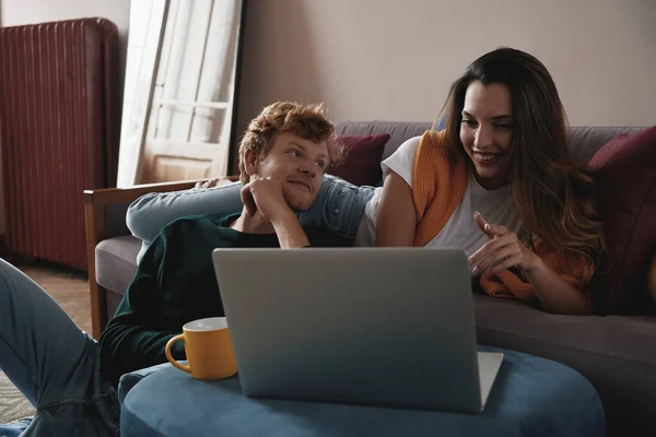 年轻貌美的夫妻一起在家里放松的时候 一边用笔记本电脑一边笑 — 图库照片