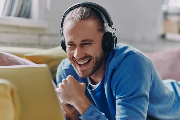 Hombre Guapo Auriculares Mirando Computadora Portátil Sonriendo Mientras Está Acostado — Foto de Stock