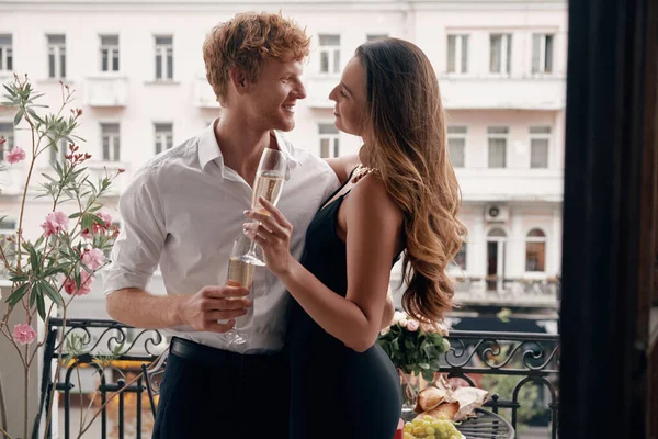 Счастливая Молодая Пара Формальной Одежде Обнимается Наслаждаясь Шампанским Балконе Вместе — стоковое фото