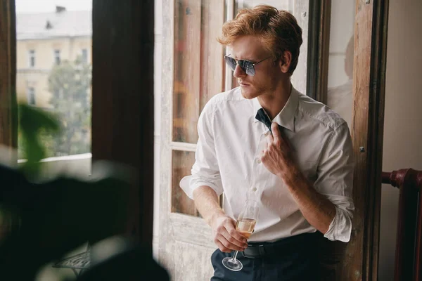 Homem Elegante Ajustando Sua Gravata Enquanto Desfruta Champanhe Porta Varanda — Fotografia de Stock