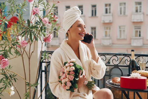 Счастливая Женщина Халате Разговаривает Мобильному Телефону Держа Букет Цветов Балконе — стоковое фото