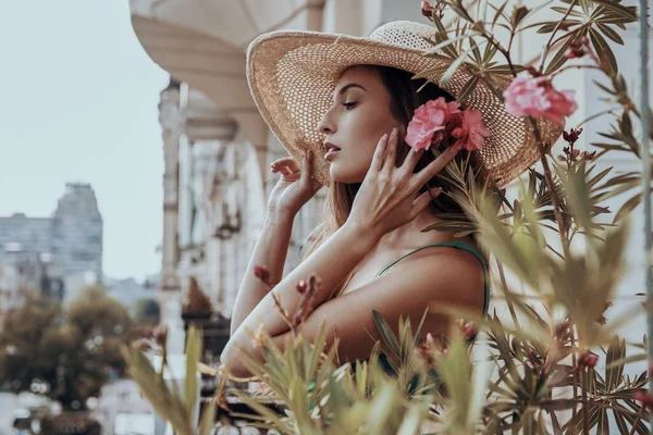 Ελκυστική Νεαρή Γυναίκα Κομψό Καπέλο Κρατώντας Λουλούδια Κοντά Στο Πρόσωπο — Φωτογραφία Αρχείου