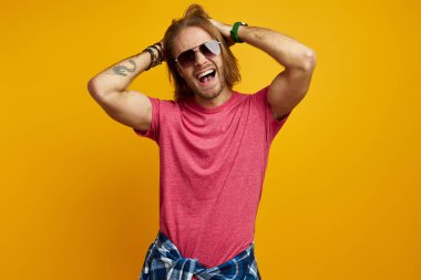 Yakışıklı genç adam işaret ediyor ve gülümsüyor sarı arka planda dururken