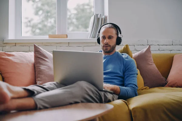 Hombre Joven Concentrado Auriculares Que Trabajan Ordenador Portátil Mientras Está — Foto de Stock