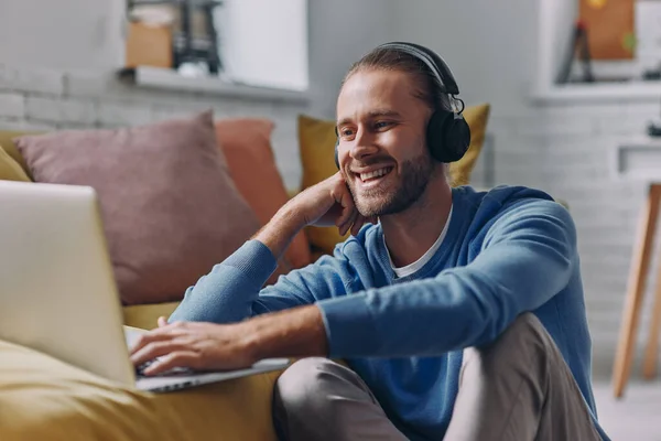 Joven Guapo Con Auriculares Usando Portátil Sonriendo Mientras Está Sentado — Foto de Stock