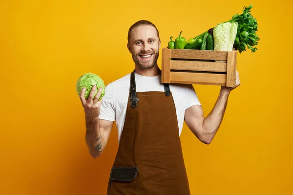 Happy Young Man Carrying Wooden Crate Fresh Veggies Yellow Background — Stock Photo, Image