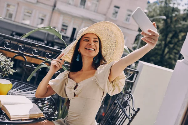 Счастливая Молодая Женщина Элегантной Шляпе Делает Селфи Смартфону Расслабляясь Балконе — стоковое фото