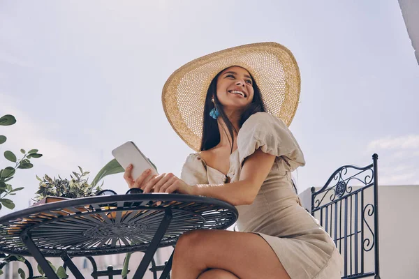Счастливая Молодая Женщина Элегантной Шляпе Держа Смартфон Расслабляясь Балконе — стоковое фото