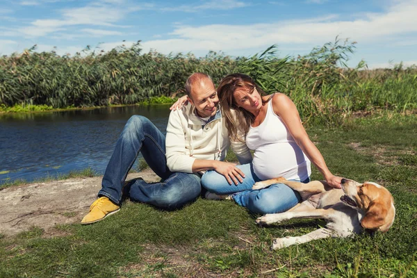 Casal com cão sentado em um parque — Fotografia de Stock