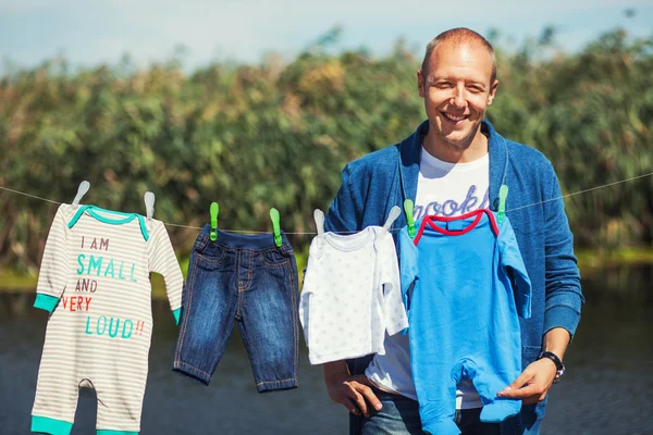 Smiling husband next to baby clothes — Stock Photo, Image