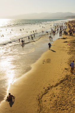 Santa monica kumsalda yürüyen insanlar