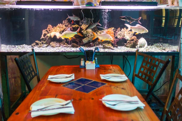 Aquarium close to a table inside a restaurant — Stock Photo, Image