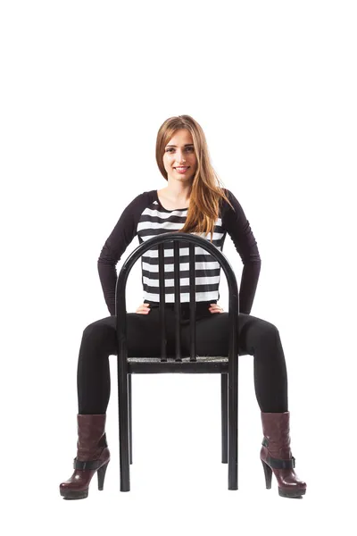Mulher sentada em uma cadeira e de mãos dadas nos quadris — Fotografia de Stock