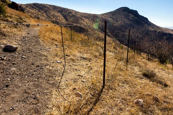 乾燥植物に覆われた山を草原の気候から隔てる鉄条網で作られたフェンス — ストック写真