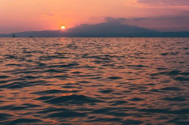 Tepelerin ardında etkileyici bir günbatımının güzel pozu. Denizden görünüm.