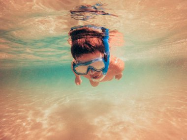 Suyun altında tek başına dalış yapan bir çocuğun resmi. Yeni bir dünya keşfediyor. .