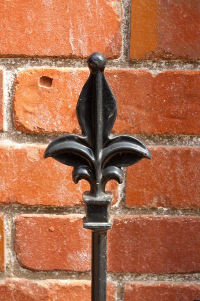 Part of an iron gate against red brick wall — Stock Photo, Image