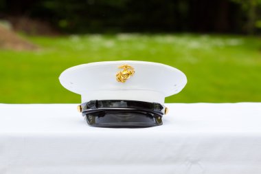 A marines hat off his head while at a wedding in uniform for armed forces soldiers and family. clipart