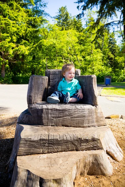 Pojken sitter på stubben stol — Stockfoto