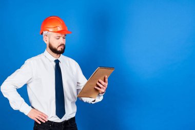 Kasklı, çekici, başarılı bir inşaat işçisi hesaplamaları, çizimleri inceliyor ve bir nesnenin yapısına odaklanıyor. İnşaat, mühendislik ve mimari kavramı..