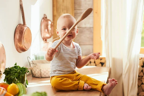 Sarı pantolonlu neşeli çocuk mutfak masasında oturuyordur. Baba oğluyla sağlıklı yemek pişirir. Vejetaryenlik kavramı, çocuklar vejetaryendir, etin reddedilmesi....
