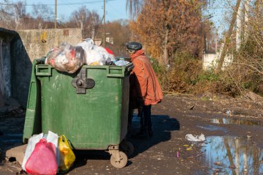 Yuryev-Polsky, Rusya, 10.30.2021 çöp tenekelerinde yaşlı bir kadın yiyecek ve giyecek arıyor.