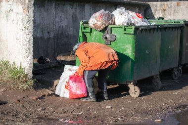 Yuryev-Polsky, Rusya, 10.30.2021 çöp tenekelerinde yaşlı bir kadın yiyecek ve giyecek arıyor.