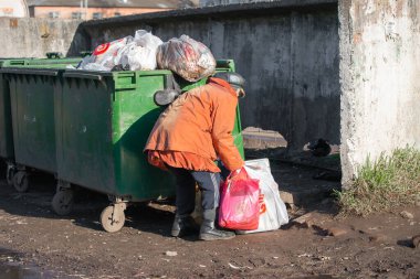 Yuryev-Polsky, Rusya, 10.30.2021 çöp tenekelerinde yaşlı bir kadın yiyecek ve giyecek arıyor.