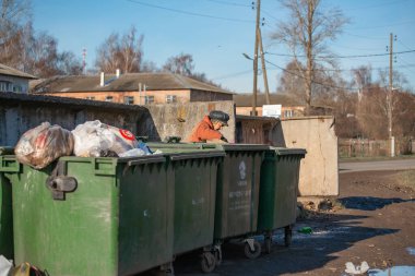 Yuryev-Polsky, Rusya, 10.30.2021 çöp tenekelerinde yaşlı bir kadın yiyecek ve giyecek arıyor.