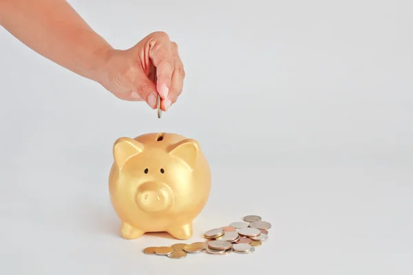 Invoegen van een munt in een piggy bank Stockafbeelding