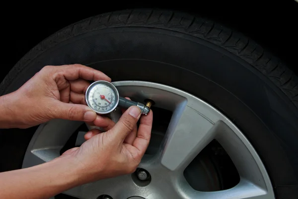 Control de presión de neumáticos por mecánico de coche al aire libre Imagen De Stock