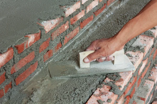 Smutsiga murslev med handske hand puts cement murbruk i wal — Stockfoto