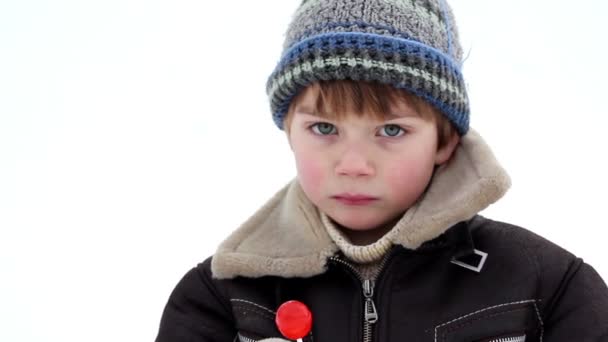 Boy in winter eating a lollipop, boy eating candy,boy licks lollypop,emotional boy, — Stock Video