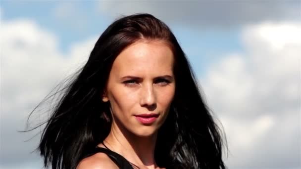 Porträtt av ung vacker kvinna på bakgrund av himlen — Stockvideo