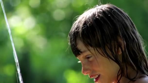 少年の少年彼の顔を洗って、庭の水で遊ぶ — ストック動画