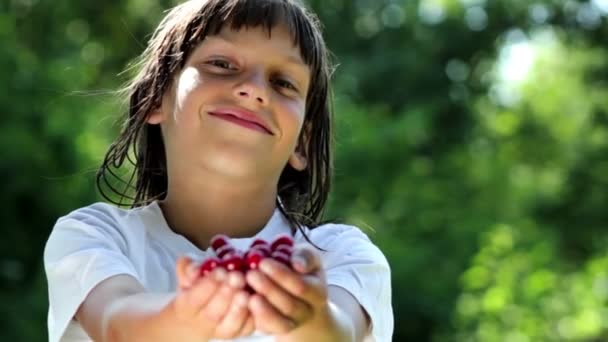 Chlapec ukazuje třešně v rukou do komory — Stock video