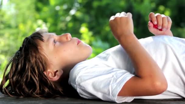 Garçon allongé manger des cerises — Video