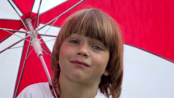 Jongen met paraplu, jongen onder een paraplu in de regen — Stockvideo