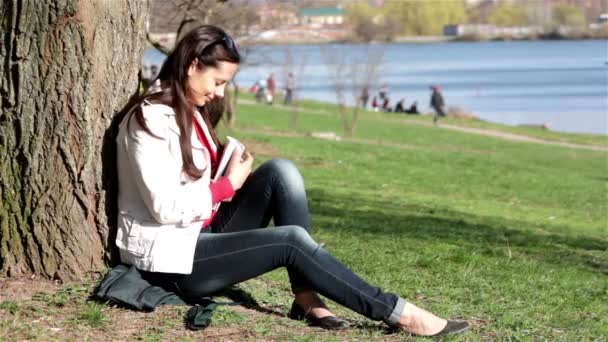 Estudiante feliz haciendo deberes en el parque de la ciudad.Estudiante feliz leyendo libro en el parque de la ciudad . — Vídeo de stock