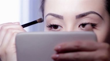 makyaj aynası, tam yüz, bulanık background.beautiful genç kızın önünde genç bir kadın makeup.young kadın ayna ve makyaj fırçası ile yapıyor.