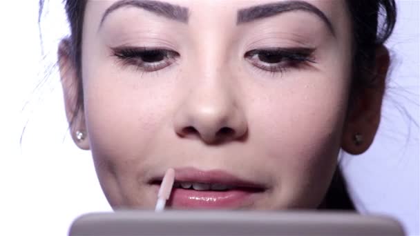 Mujer joven haciendo maquillaje delante de un espejo, cara completa, fondo borroso. Hermosa chica joven está haciendo maquillaje. Mujer joven con espejo y cepillo de maquillaje . — Vídeos de Stock