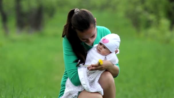 En ung mor med en baby på våren — Stockvideo