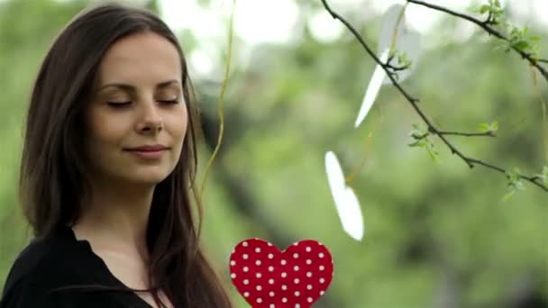 Jovem menina bonita com um coração de papelão em sua mão conceito de amor — Vídeo de Stock